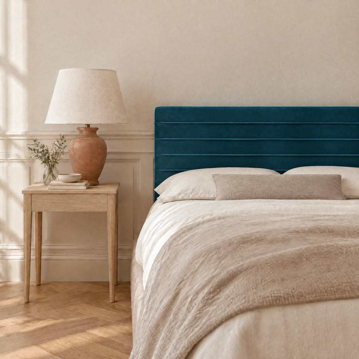 Tête de lit en velours bleu canard devant un mur clair