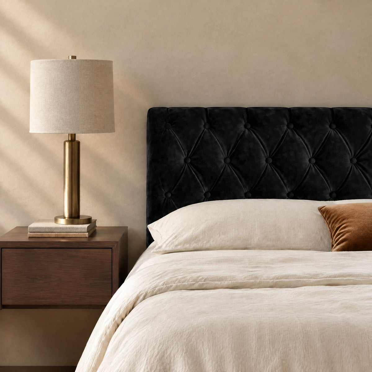 Tête de lit capitonnée en velours Alma noir dans une chambre, avec table de chevet et lampe