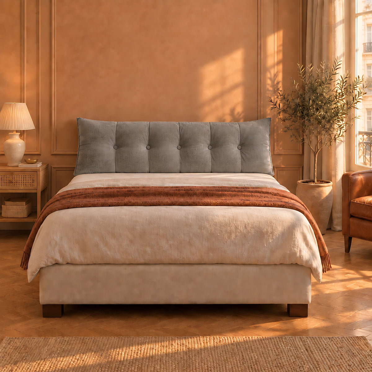 Coussin de tête de lit Opéra gris posé sur un lit sans oreillers