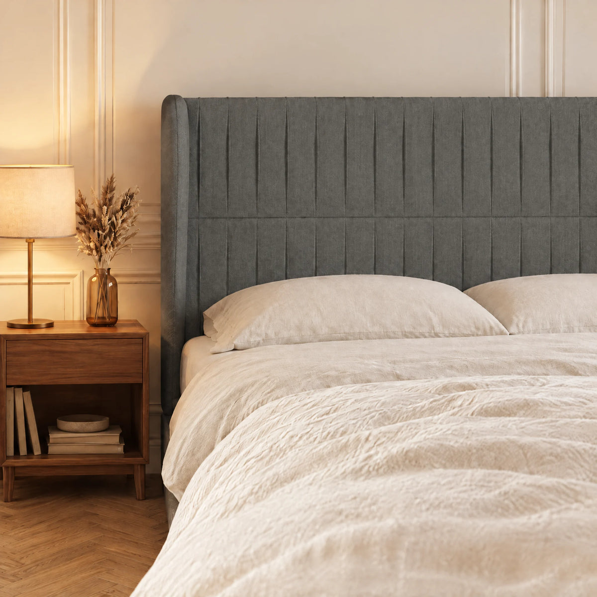 Tête de lit haute cannelée à oreilles en tissu Friedland gris anthracite dans une chambre, avec table de chevet et lampe