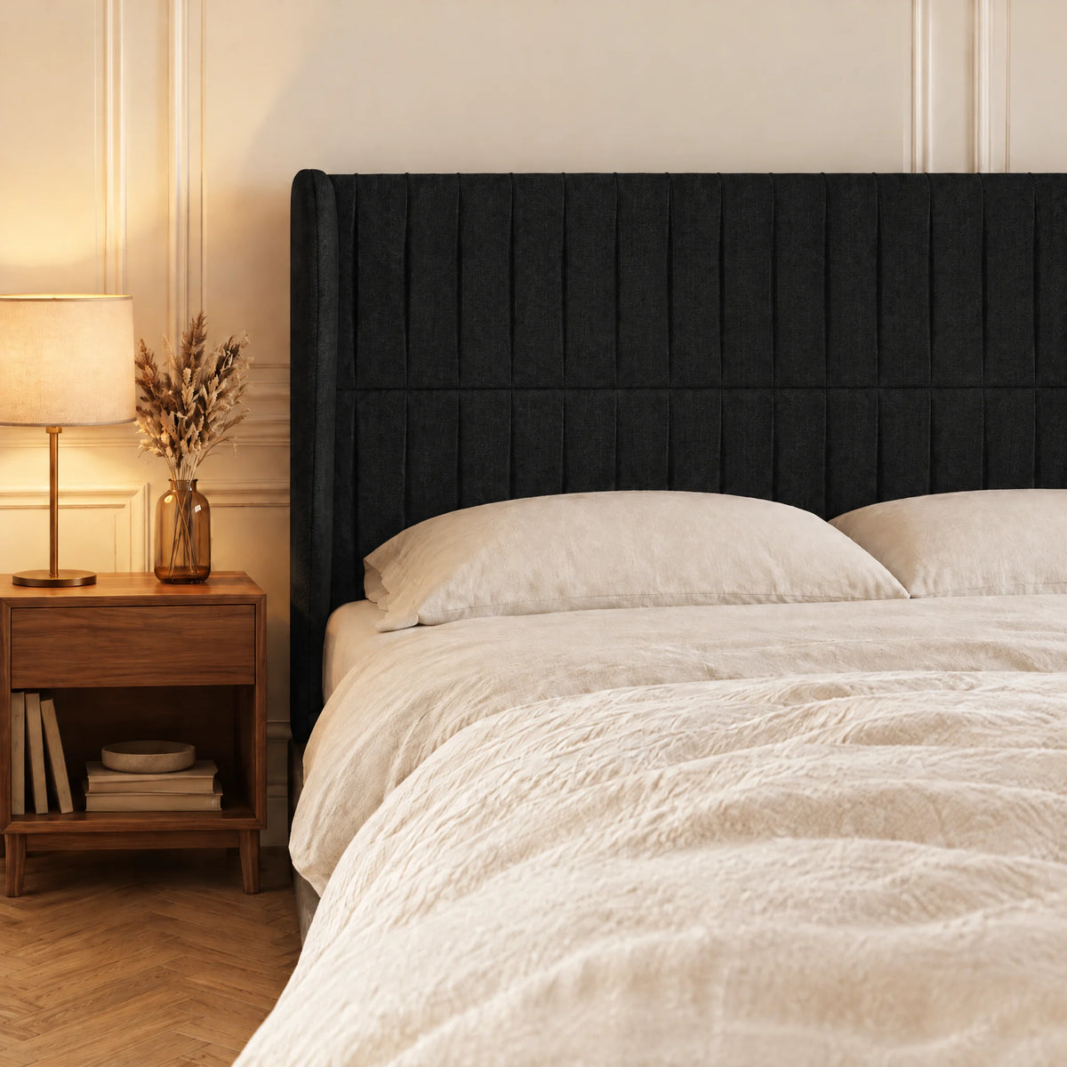 Tête de lit haute cannelée à oreilles en tissu Friedland noir dans une chambre, avec table de chevet et lampe
