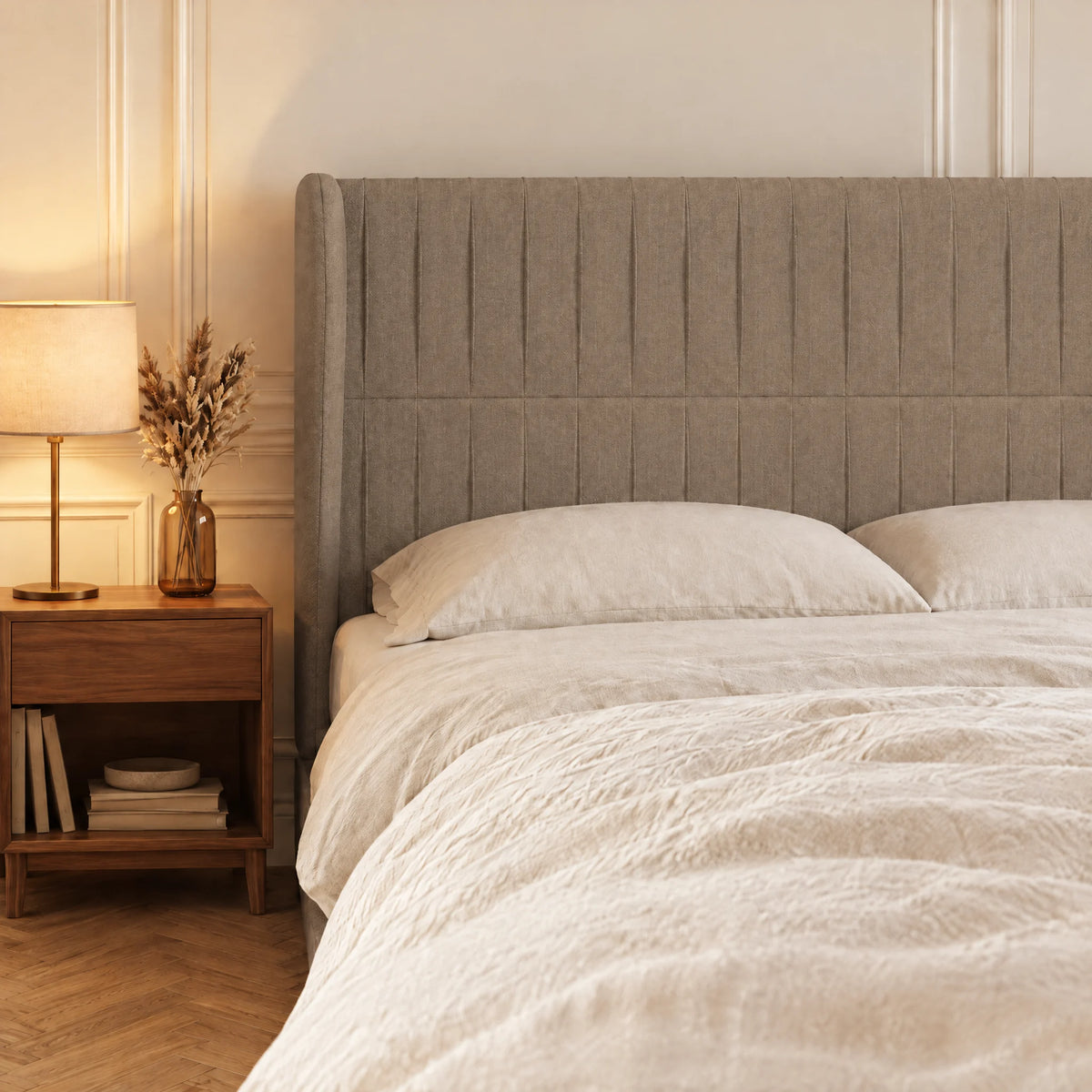 Tête de lit haute cannelée à oreilles en tissu Friedland taupe dans une chambre, avec table de chevet et lampe
