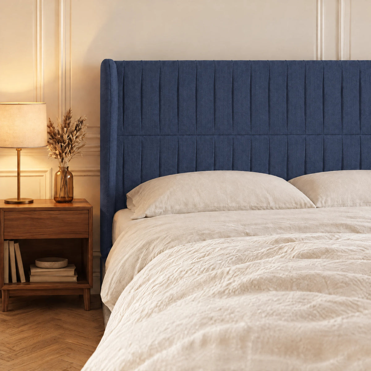 Tête de lit haute cannelée à oreilles en tissu Friedland bleu dans une chambre, avec table de chevet et lampe