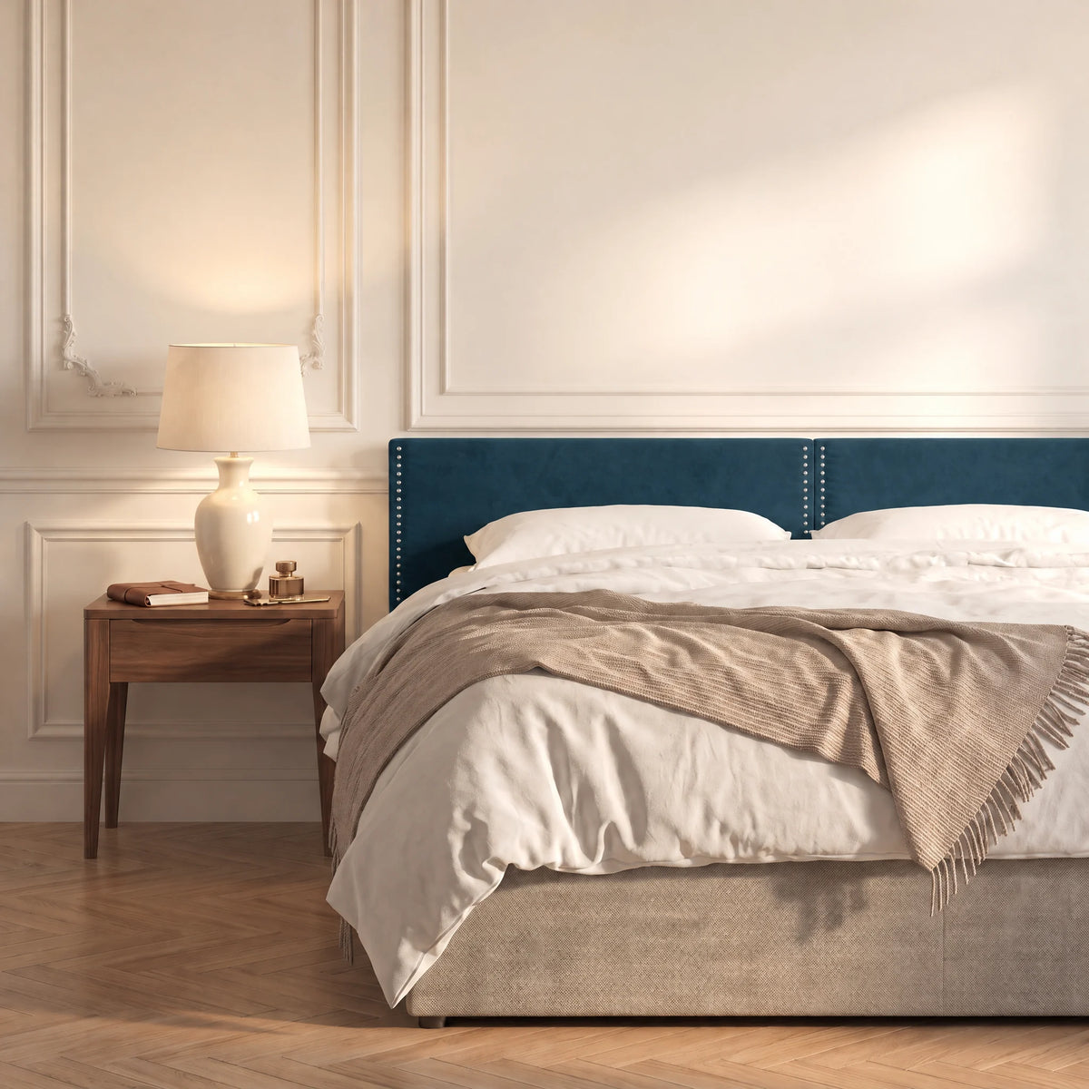 Tête de lit cloutée en velours à poser Saint-Louis bleu canard dans une chambre, avec table de chevet et lampe