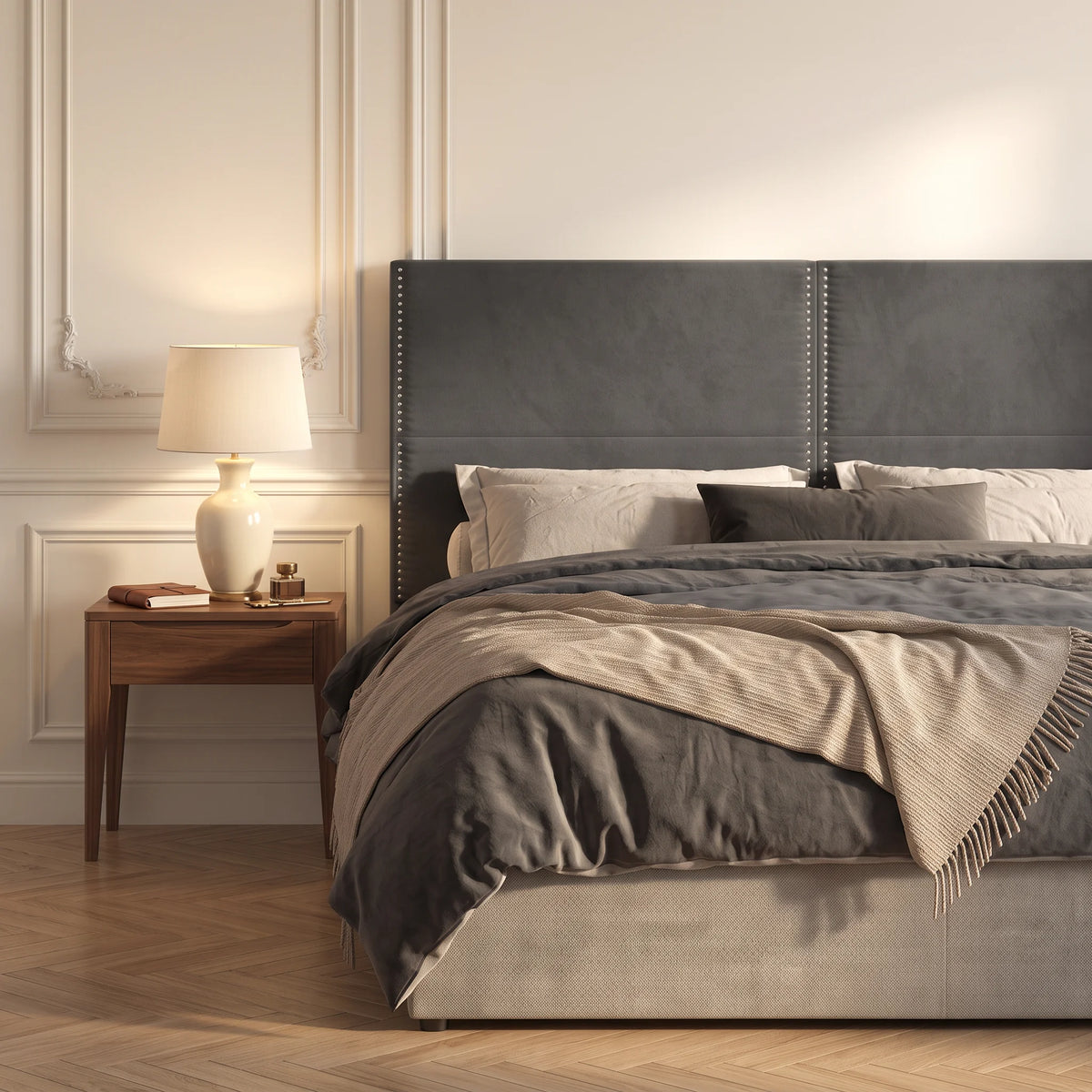 Tête de lit haute cloutée en velours Matignon gris anthracite dans une chambre, avec table de chevet et lampe