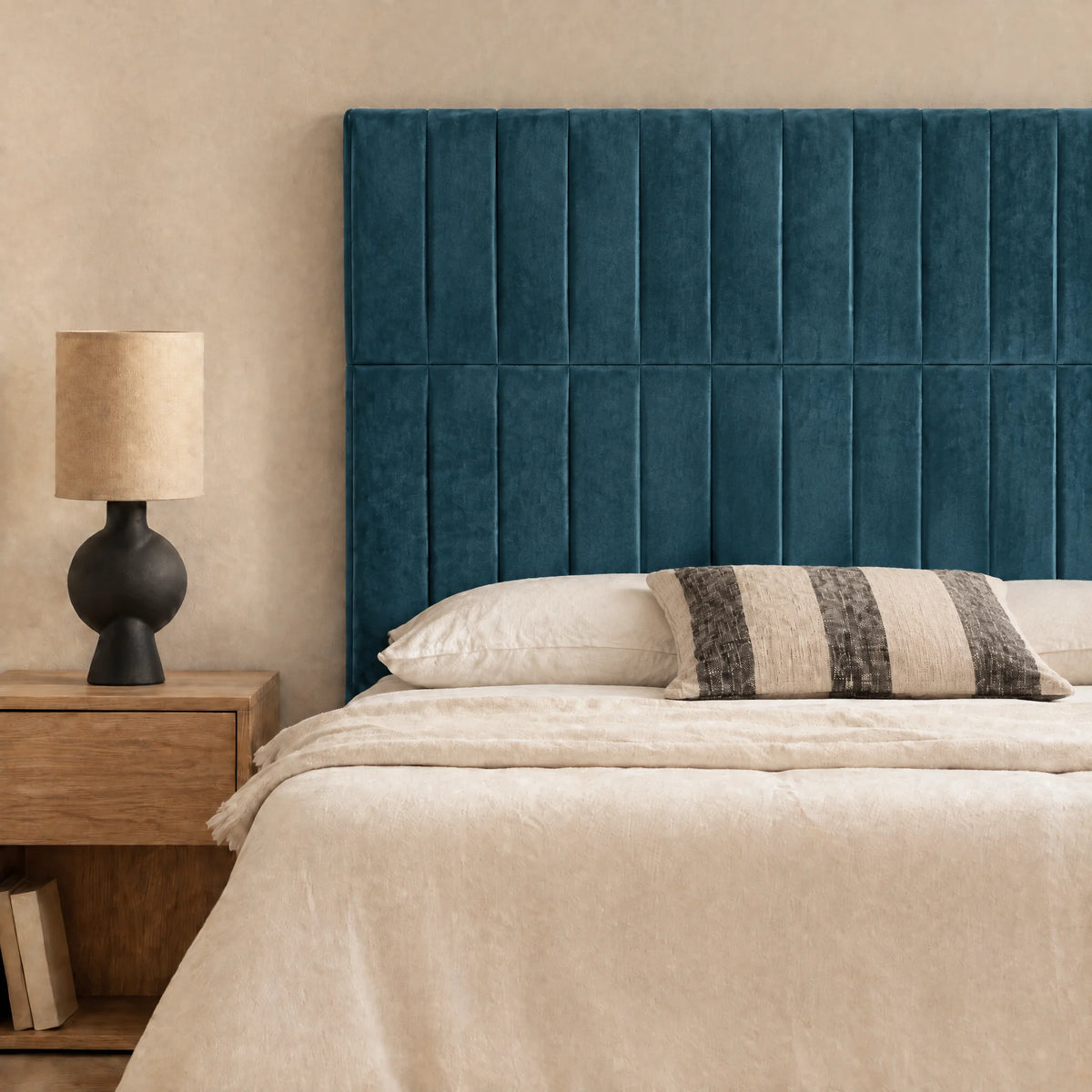Tête de lit haute en velours Étoile bleu canard dans une chambre, avec table de chevet et lampe