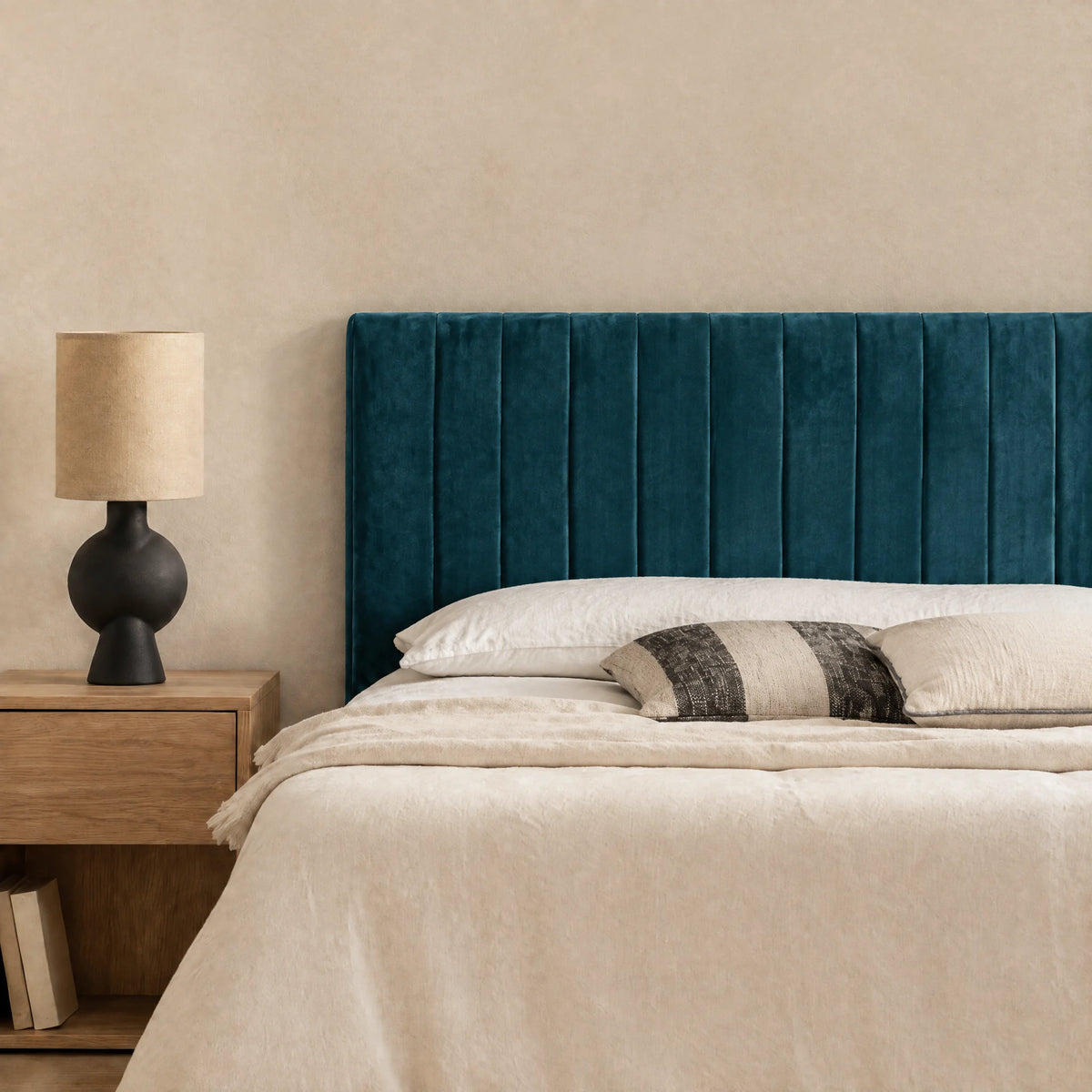 Tête de lit en velours Madeleine bleu canard dans une chambre, avec table de chevet et lampe