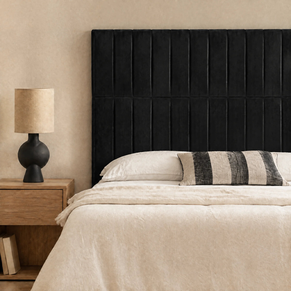 Tête de lit haute en velours Étoile noir dans une chambre, avec table de chevet et lampe