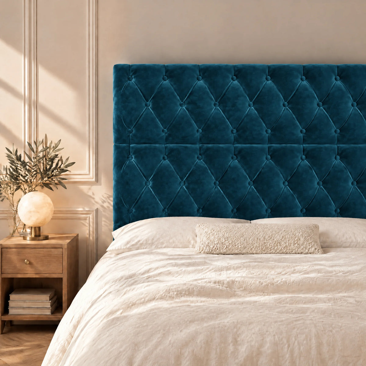 Tête de lit haute capitonnée en velours Concorde bleu canard dans une chambre, avec table de chevet et lampe