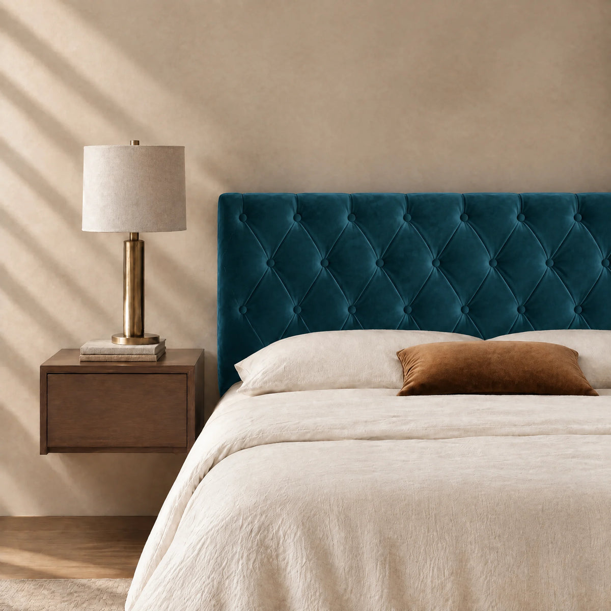 Tête de lit capitonnée en velours Alma bleu canard dans une chambre, avec table de chevet et lampe