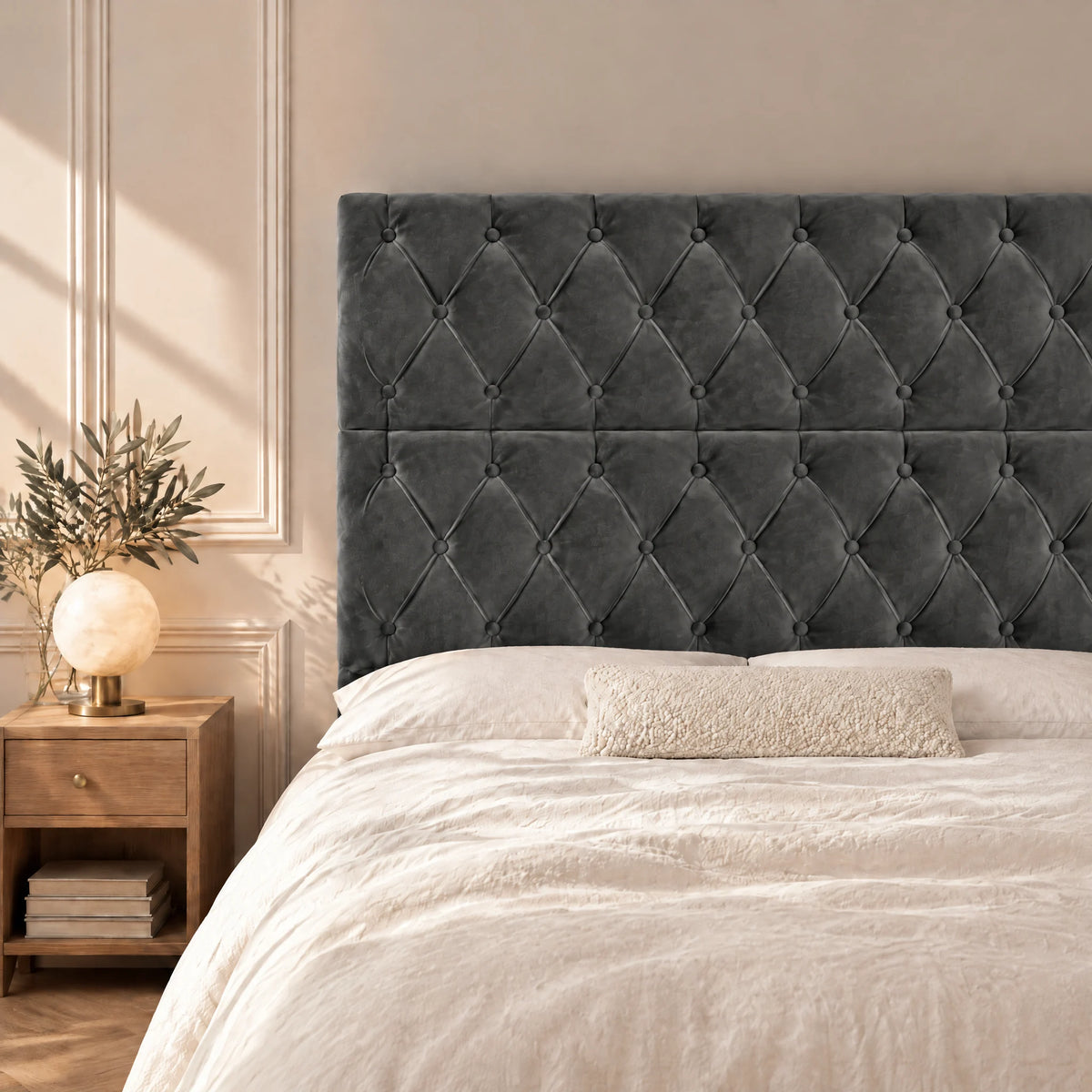 Tête de lit haute capitonnée en velours Concorde gris anthracite dans une chambre, avec table de chevet et lampe