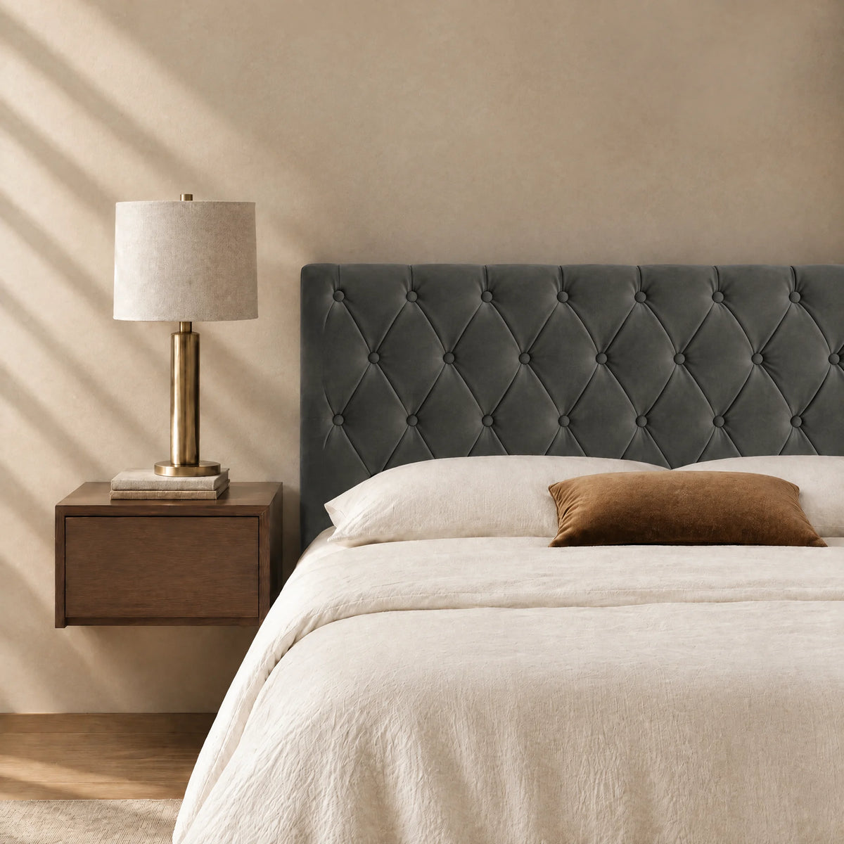 Tête de lit capitonnée en velours Alma gris anthracite dans une chambre, avec table de chevet et lampe
