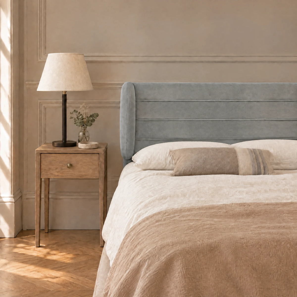 Tête de lit à oreilles en velours ligné Chaillot gris clair dans une chambre, avec table de chevet et lampe