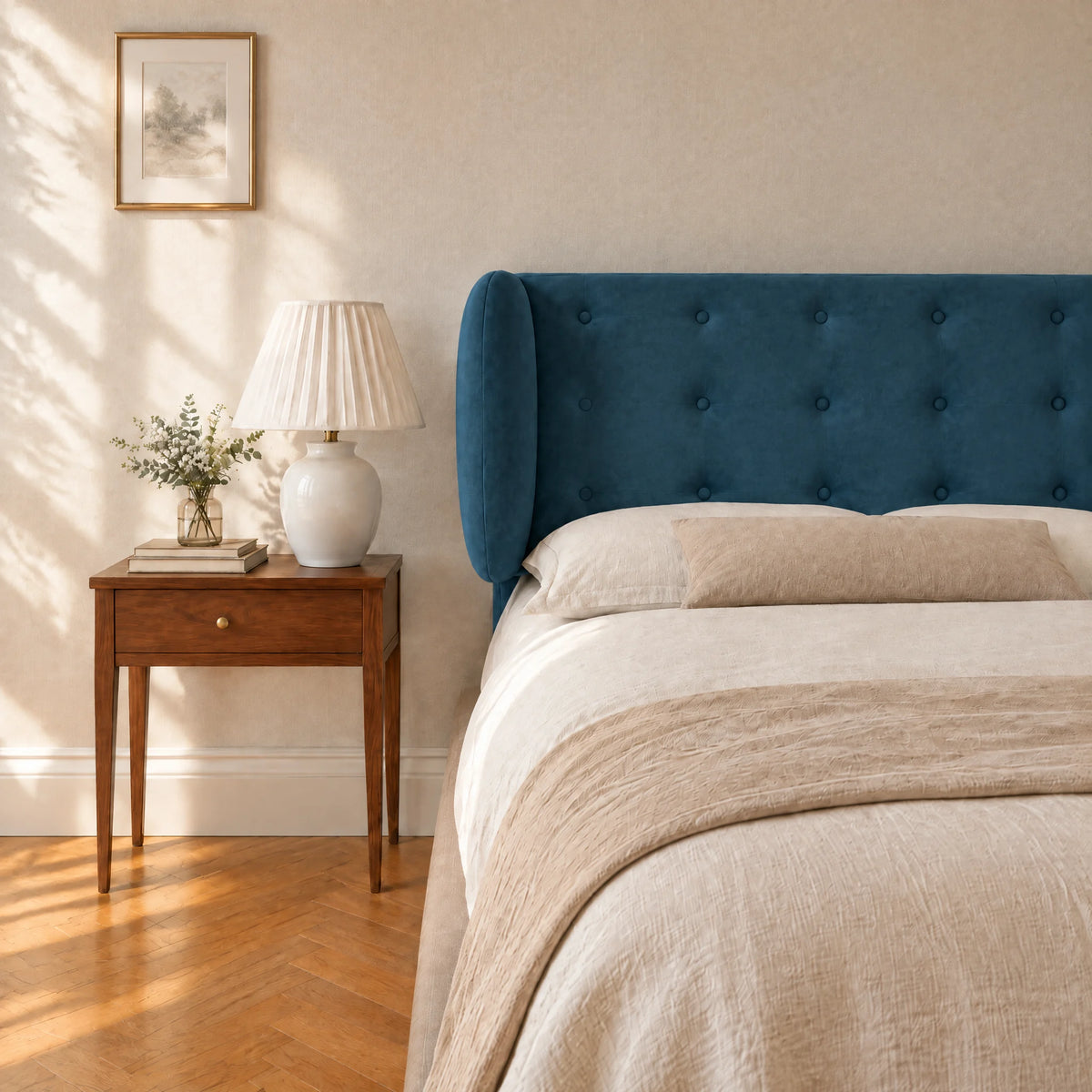 Tête de lit boutonnée à oreilles en velours Auteuil bleu canard dans une chambre, avec table de chevet et lampe