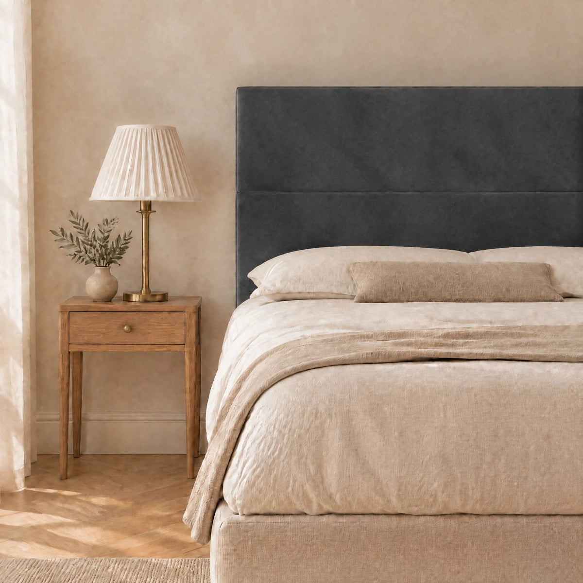 Tête de lit haute en velours lisse Châtelet gris anthracite dans une chambre, avec table de chevet et lampe