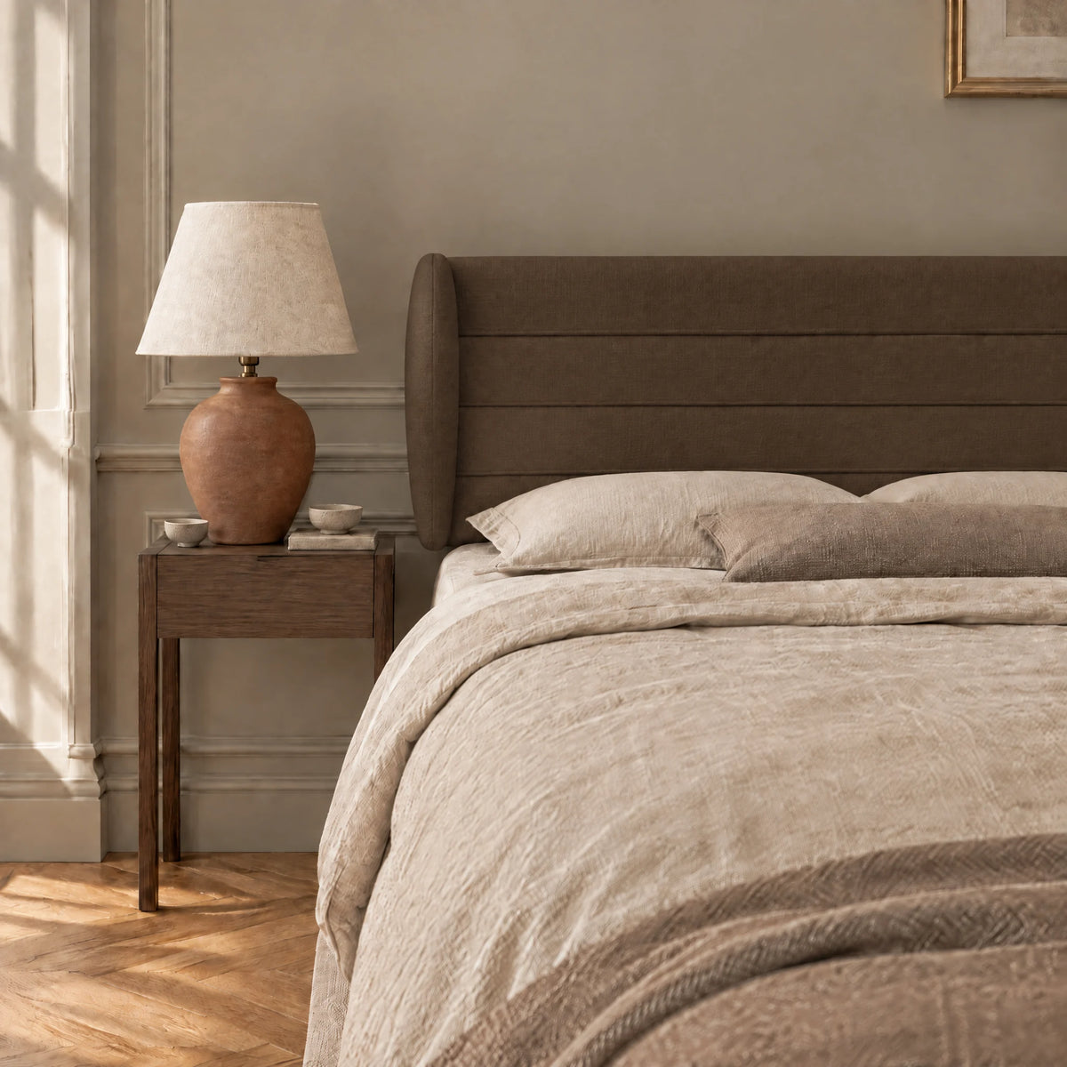 Tête de lit à oreilles en tissu Bagatelle chocolat dans une chambre, avec table de chevet et lampe