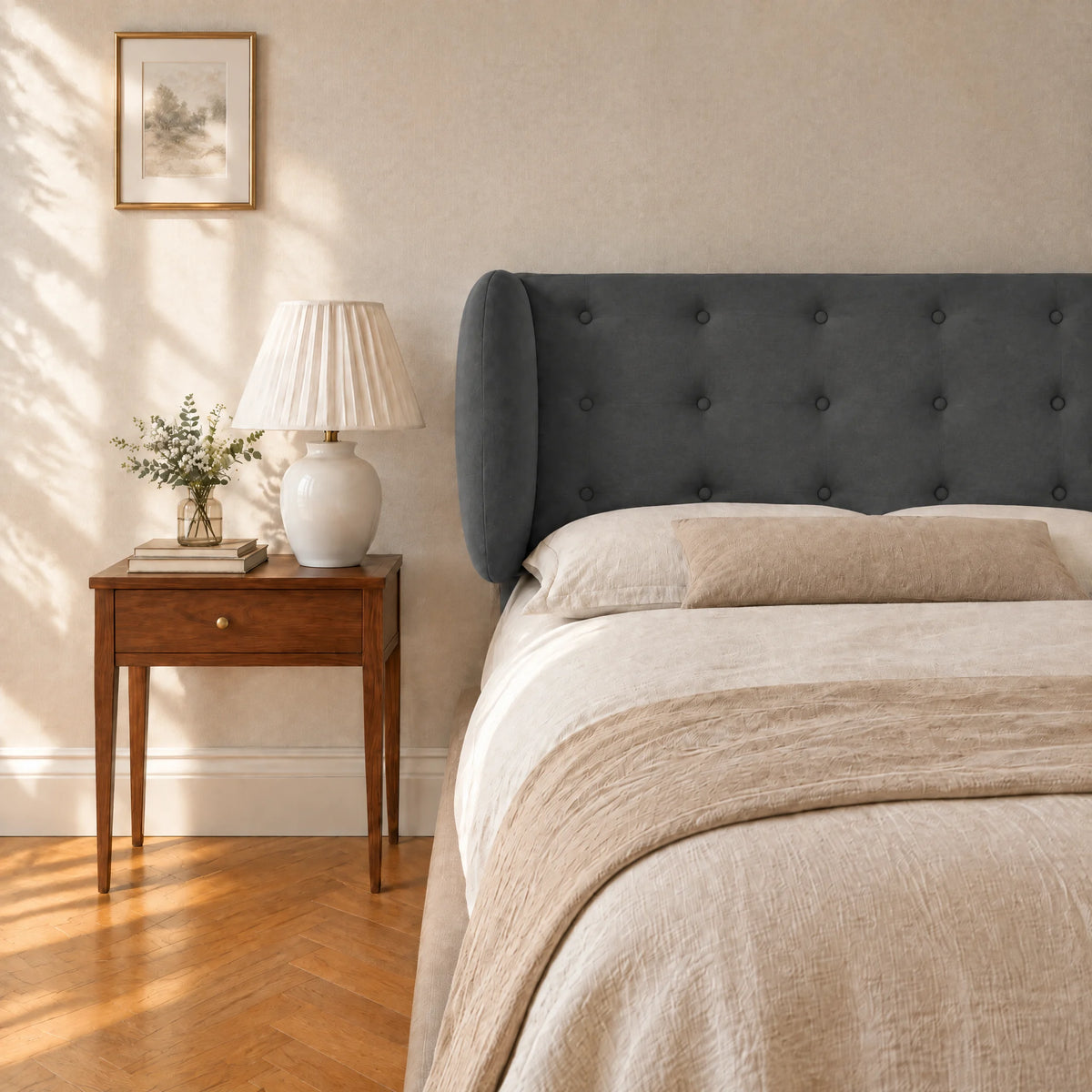 Tête de lit boutonnée à oreilles en velours Auteuil gris anthracite dans une chambre, avec table de chevet et lampe