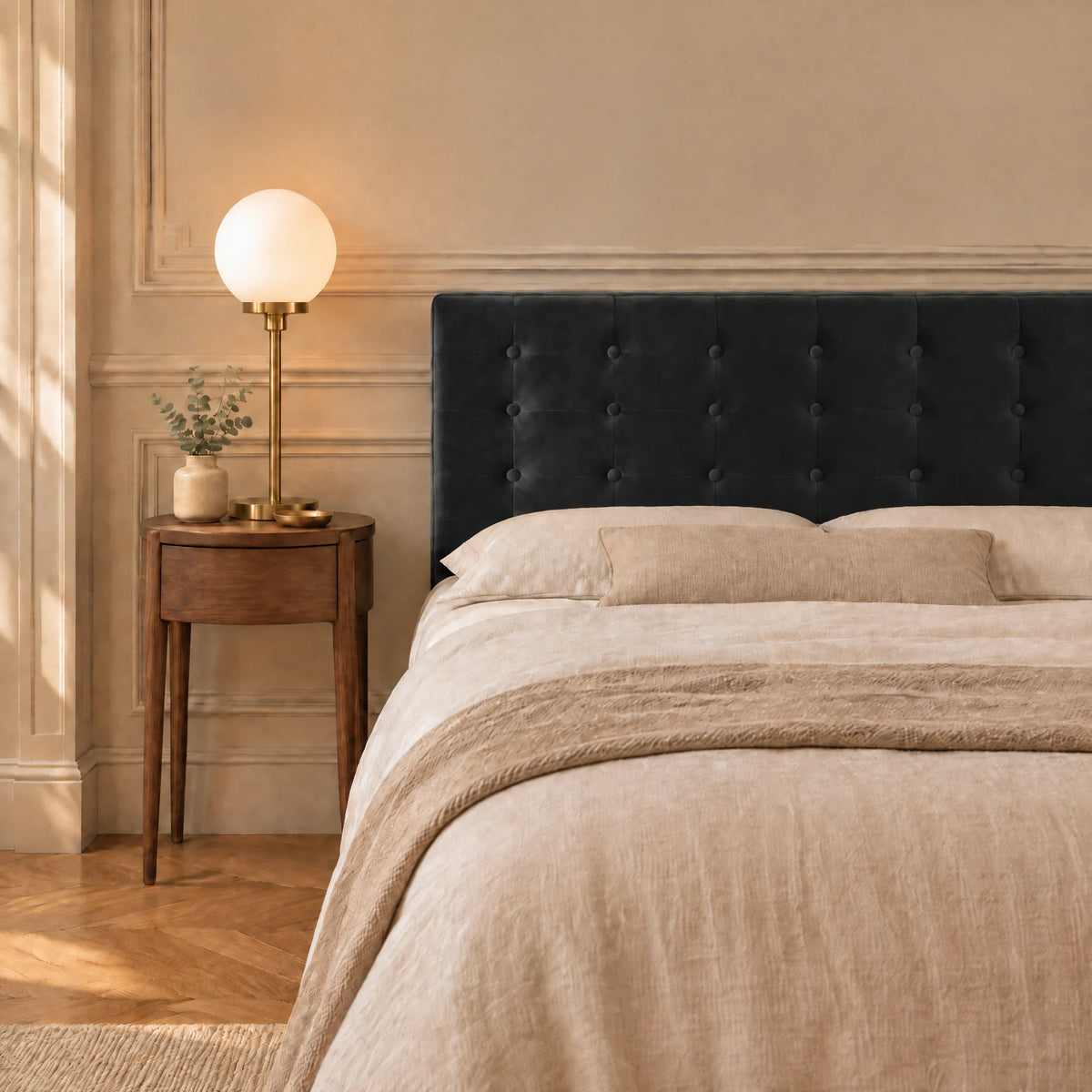 Tête de lit boutonnée en velours Dauphine noir dans une chambre, avec table de chevet et lampe