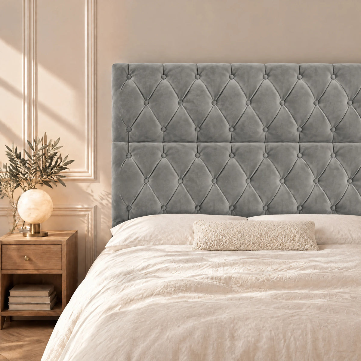 Tête de lit haute capitonnée en velours Concorde gris clair dans une chambre, avec table de chevet et lampe