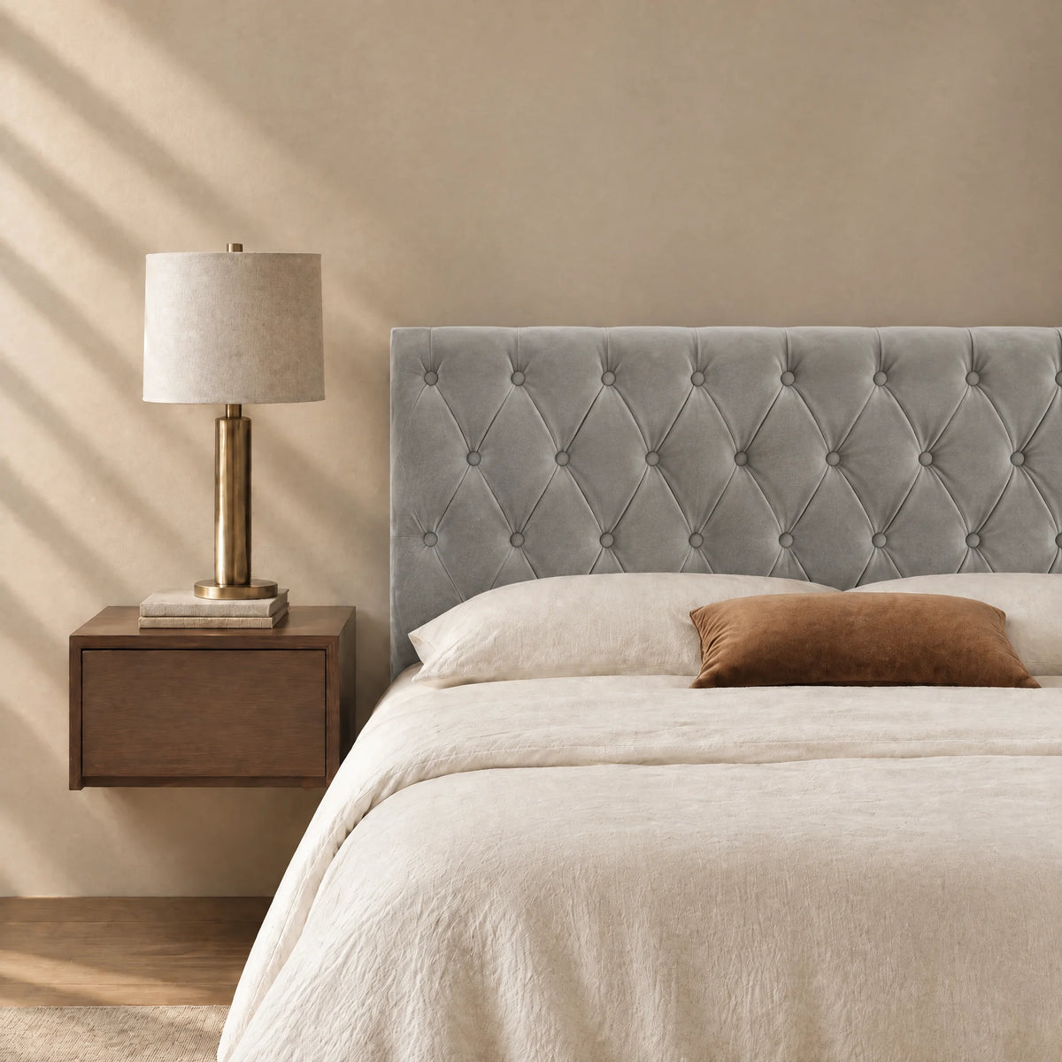 Tête de lit capitonnée en velours Alma gris clair dans une chambre, avec table de chevet et lampe