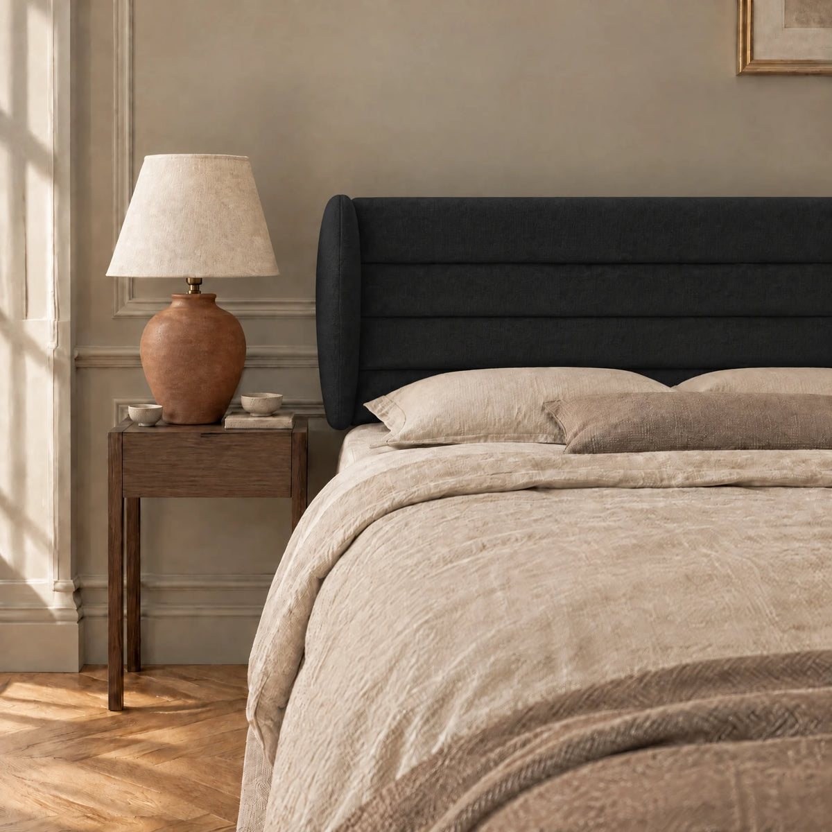 Tête de lit à oreilles en tissu Bagatelle noir dans une chambre, avec table de chevet et lampe
