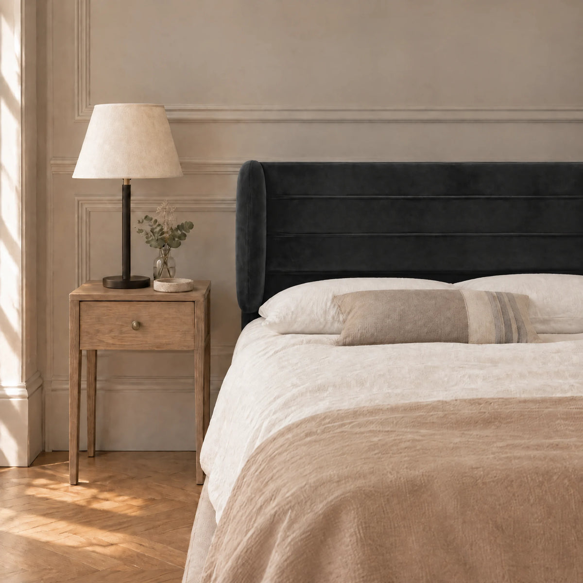 Tête de lit à oreilles en velours ligné Chaillot noir dans une chambre, avec table de chevet et lampe